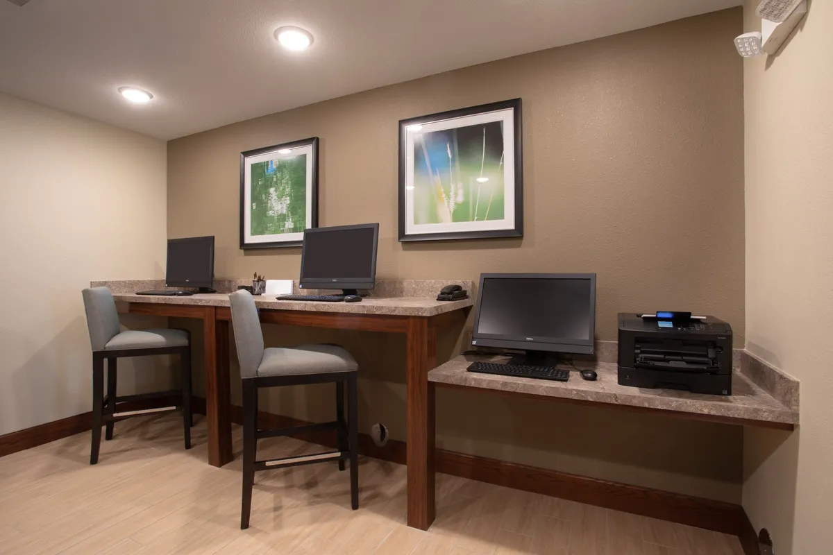 A functional yet comfortable workspace within an interior setting, featuring computers, a printer, and eye-catching artwork. The mood is focused, suggesting an environment where guests can catch up on emails, stream shows, or work remotely with ease.